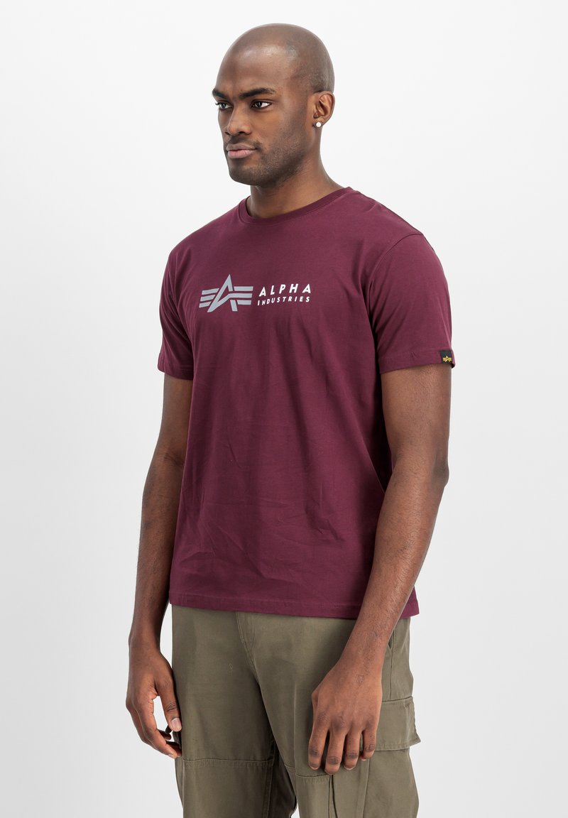 Maronfarvet bomulds t-shirt med et sølvlogo på brystet, korte ærmer og en afslappet pasform. Enkel design med en subtil tekstur.