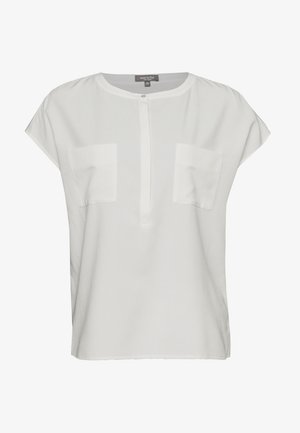 Blouse blanche à manches courtes avec un col rond, deux poches poitrine et un plastron à boutons, fabriquée à partir d'un tissu lisse et léger.