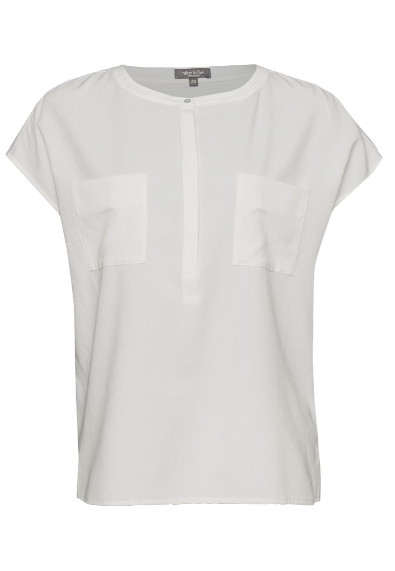 Blouse blanche à manches courtes avec un col rond, deux poches poitrine et un plastron à boutons, fabriquée à partir d'un tissu lisse et léger.