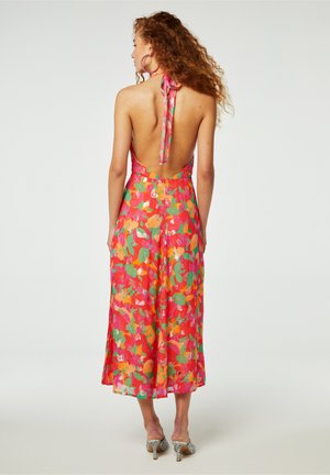 Kleurrijke mouwloze jurk met een halternek, open rug en bloemmotief in roze, groen, oranje en zilveren accenten. Middellange uitvoering.