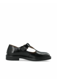 Black leather Mary Jane shoe with a rounded toe, cut-out detail, and adjustable strap. Features a low, flat sole and smooth texture.