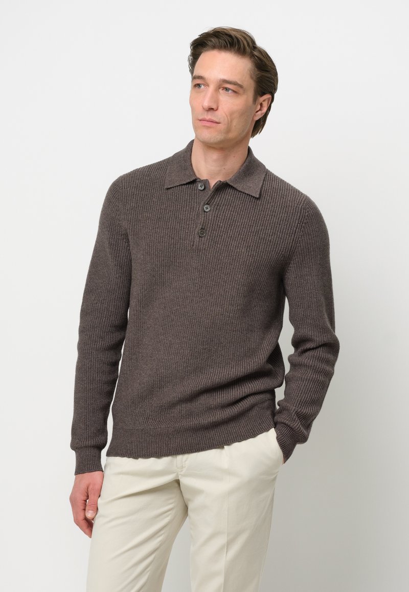 Pulóver marrón de punto acanalado con cuello y tapeta de tres botones, combinado con pantalones de color claro. Presenta mangas largas y un acabado texturizado.