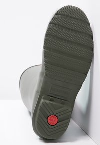 Zelená gumená bootka s textúrovanou podrážkou, červeným akcentom a embosovaným logom na päte. Hladký povrch a vysoký strih.