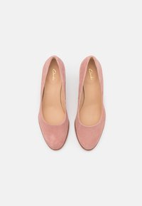 Ballerines en daim rose avec un bout arrondi, un intérieur lisse et un design minimaliste. Logo Clarks embossé sur la semelle intérieure. Aucun élément métallique visible.
