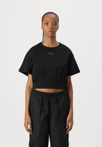Svart kortärmad t-shirt i mjukt material med korta ärmar, med en diskret logotyp på bröstet och matchande löst sittande svarta byxor.