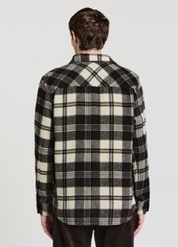 Schwarz-cremefarbenes kariertes Flanellhemd mit langen Ärmeln, spitzem Kragen und geknöpften Manschetten. Weiche Textur und leicht geschwungener Saum.