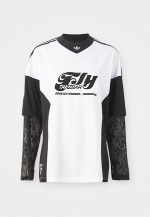 Balta un melna sporta krekls ar gariem mežģīņu piedurknēm, ar melnu grafisko izdruku, kurā rakstīts "Fly Tanzbar", un Adidas logotipu.