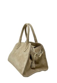 Krémová semišová kabelka se strukturovaným tvarem, dvojitými horními uchy a zipovou kapsou. Obsahuje zlaté kovové detaily.