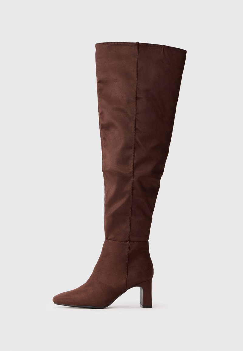 Barna, térd fölé érő csizma, puha, velúr-szerű anyagból készült. Jellemzője a hegyes orr és a réteges sarkak a stabilitás érdekében. Simább, matt felület.