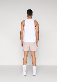 Valge varrukateta tankitopp, beežid lühikesed püksid, sportlikud sokid ja tossud. Omadused lihtsa disaini, sileda tekstuuri ja puhaste joontega.