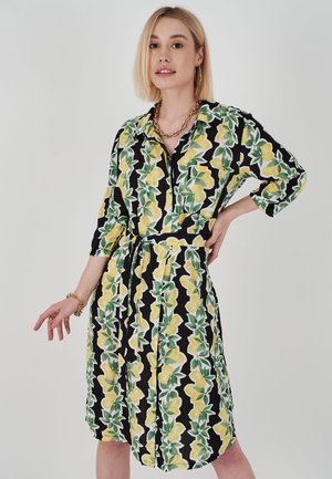 Schwarzes Kleid mit einem Muster aus Zitronen und grünen Blättern, mit einem kragenlosen Ausschnitt, langen Ärmeln und einem gebundenen Taillengürtel für eine anpassbare Passform.