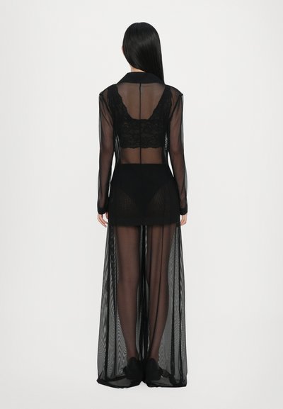 Schwarzes, transparentes langes Kleid mit Spitzenverzierungen, vorderem Schlitz und langen Ärmeln. Verfügt über einen hohen Kragen und ist über einen eng anliegenden schwarzen Body geschichtet.