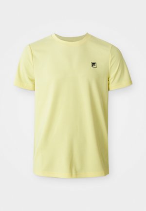 Camiseta de manga corta amarilla claro con cuello redondo y pequeño logo negro en el lado izquierdo del pecho, exhibida sobre un fondo blanco.