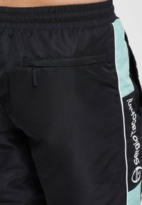 Shorts atletici negri cu un finisaj texturat, dotati cu un buzunar lateral, accente mint verzi si un logo alb pe picior.