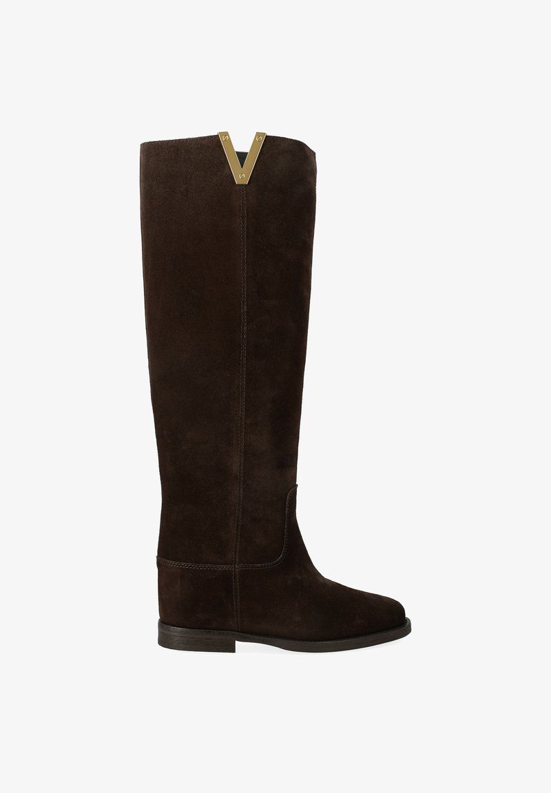 Bottines en daim marron foncé jusqu'au genou avec semelle plate et accent en métal doré en forme de V au bord supérieur.