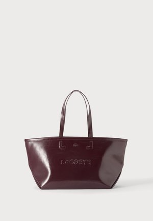 Sac cabas Lacoste bordeaux brillant avec deux longues poignées, présenté sur un fond clair uni.