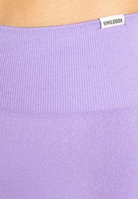 Fliederfarbenes, geripptes Gewebe mit glatter Textur. Oben befindet sich ein gebrandetes Etikett "SMILODOX" und zeigt ein figurbetontes Design.