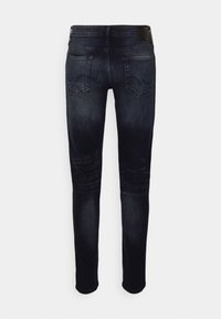 Tmavě modré slim-fit džíny s vybledlými záhyby, dvěma zadními kapsami se švy a černou koženou nášivkou značky na pasu.
