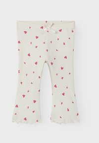 Helle cremefarbene Leggings aus weicher Baumwolle, mit einem Muster aus kleinen rosa Herzen und einer dekorativen Schleife an der Taille, mit geschwungenen Säumen.