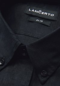 Czarna, dopasowana koszula z kołnierzykiem, wykonana z teksturowanej tkaniny, z dwoma czarnymi guzikami w pobliżu kołnierza. Metka z napisem "LANCERTO SLIM."