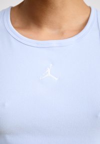 Canotta a coste di colore azzurro chiaro con scollo rotondo e logo Jumpman ricamato in bianco sul petto. Tessuto liscio e design aderente.