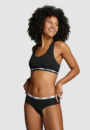 Black sports bra and matching briefs made of soft fabric, featuring a contrasting white elastic band with 'PUMA' logo. Simple, fitted design.