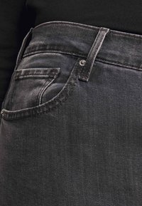 Svarta jeans i denim med hög midja, klassisk femficksdesign och synliga sömnadsdetaljer. Tyget har en subtil textur och lyster.