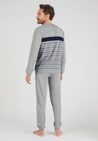 Conjunto de ropa de estar por casa en gris, con mangas largas y puños, que presenta rayas horizontales en azul marino y gris claro en la parte trasera, de textura suave.