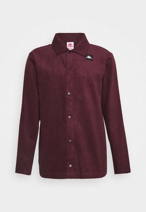 Veste en velours côtelé bordeaux à manches longues avec fermeture à boutons, col et patch logo Kappa sur la poitrine gauche.