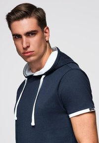 Námořnická mikina s bílou podšívkou, obsahující kapuci se šňůrkou, krátké rukávy a kontrastní bílé akcenty na manžetách.