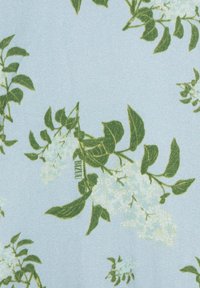 Kwiatowy materiał o jasnoniebieskim tle z zielonymi liśćmi i białymi kwiatami, prezentujący miękką teksturę i powtarzający się wzór botaniczny.