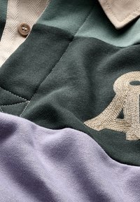 Polo shirt met een groen, lavendel en beige kleurenblokdesign, gemaakt van een textuurstof met geborduurd logo detail.