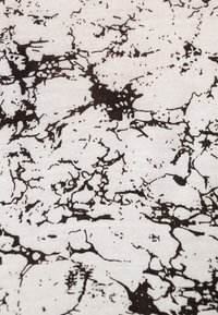 Tessuto in bianco e nero con un motivo marmorizzato caratterizzato da forme e linee irregolari su uno sfondo chiaro, evidenziando una superficie strutturata.