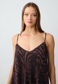 Schwarzes und burgunderfarbenes ärmelloses Cami-Top mit V-Ausschnitt, das eine gerippte Textur und ein wellenförmiges Muster auf dem Stoff aufweist.