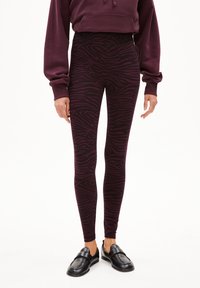 Bordeaux legging met een zwart zebra patroon, gemaakt van rekbaar stof, gecombineerd met zwarte instappers. Hoog taille ontwerp.