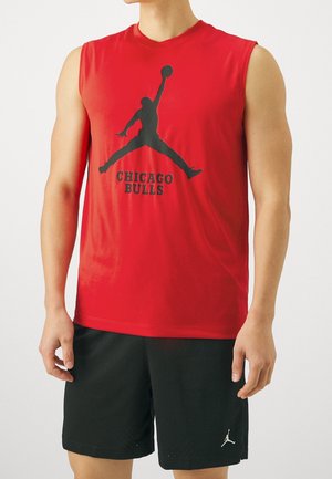 Mann trägt ärmelloses rotes Chicago Bulls Shirt mit schwarzer Basketballspieler-Silhouette und schwarze Shorts mit kleinem weißen Logo.