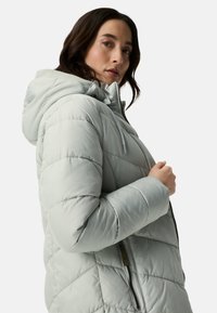 Light gray puffer jacket with a hood, featuring a quilted design, a front zipper, and elastic cuffs. Smooth, water-resistant material.
