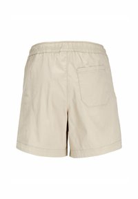 Pantalones cortos beige hechos de tela ligera, con una cinturilla elástica y un bolsillo trasero único con una tapeta rectangular.