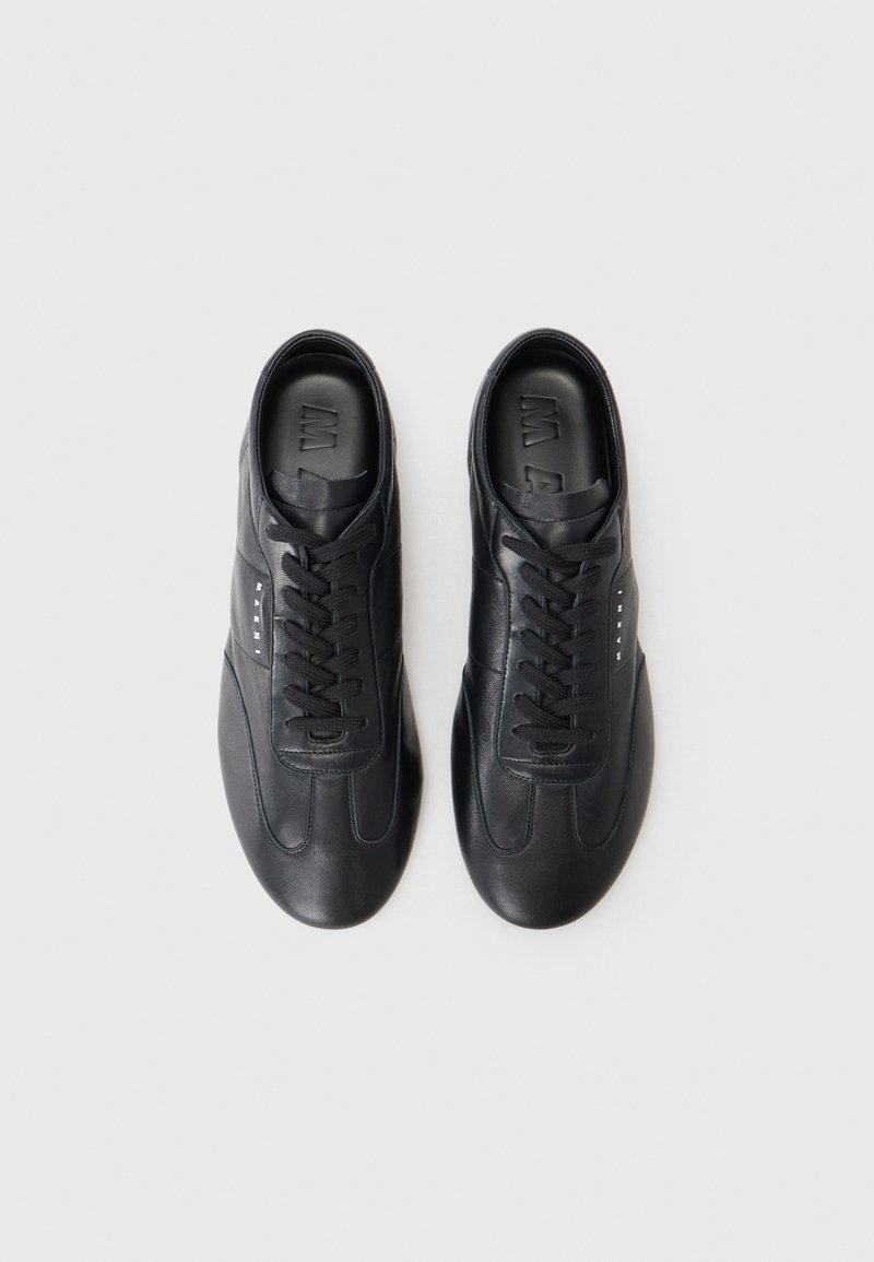 Schwarze Ledersneaker mit runden Zehen, kontrastierender Naht und flachen Schnürsenkeln. Besitzen eine glatte Textur und ein minimalistisches Design.