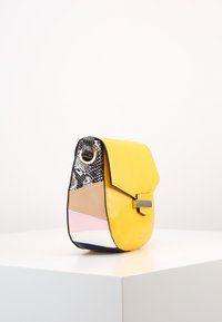 Borsa in pelle gialla con una forma strutturata. Presenta dettagli in stampa rettile nera e un design a blocchi di colore beige, rosa e blu. Finiture in argento.