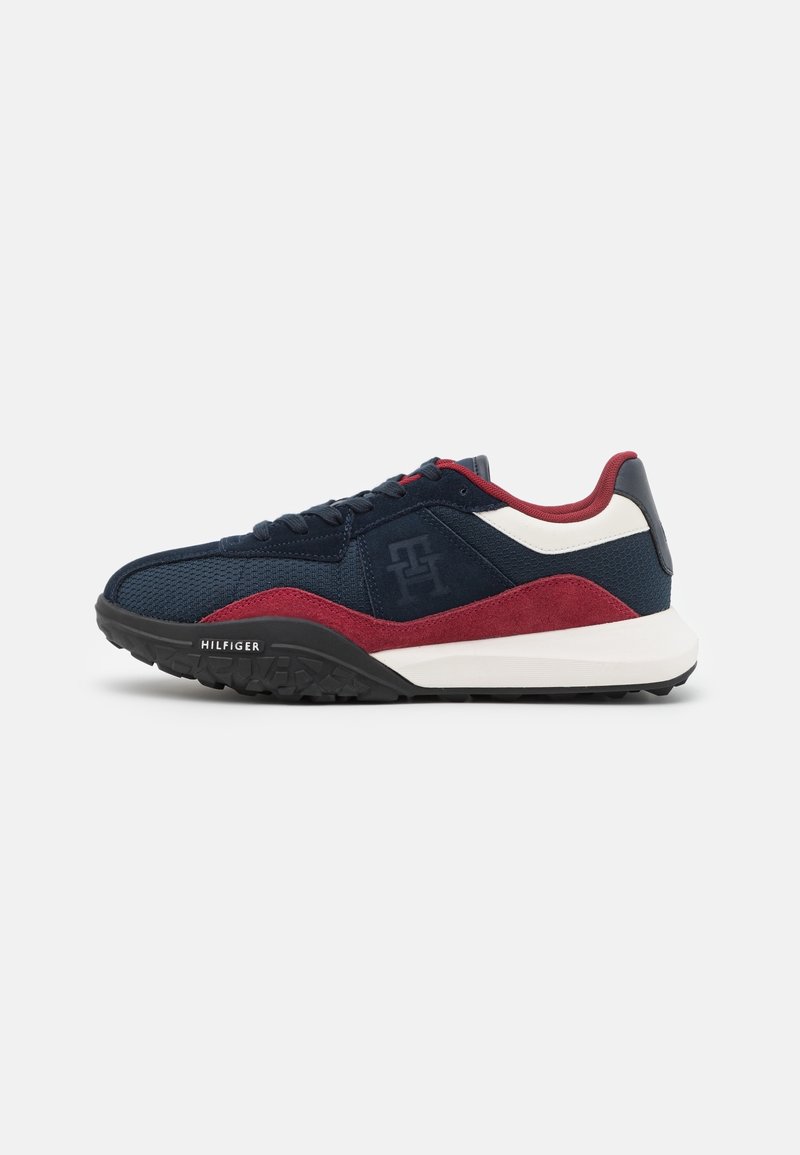 Baskets de sport bleu marine, bordeaux et blanc avec dessus texturé, semelle noire, design à lacets et logo « Hilfiger » sur le côté.