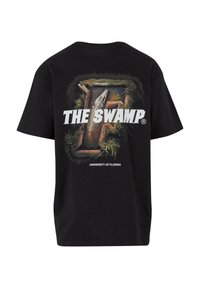 Sort t-shirt med et grafisk motiv af en alligator og teksten "THE SWAMP" og "UNIVERSITY OF FLORIDA" i fede hvide bogstaver.
