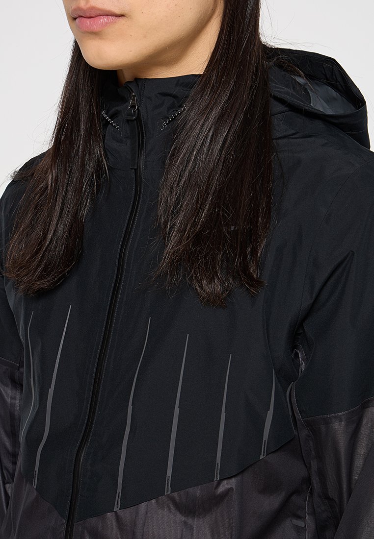 Zwarte lichtgewicht jas met een ritssluiting, capuchon en waterafstotende stof. Bevat reflecterende accenten en een gladde textuur.
