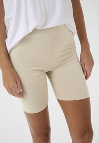 Pantalones cortos de bicicleta de mezcla de algodón color beige con una textura suave, cintura elástica y longitud corta. Diseñados para confort y facilidad de movimiento.