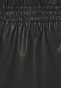 Tissu en cuir noir avec une ceinture élastique froncée, offrant une texture lisse, légèrement brillante et un subtil détail grainé.