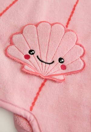 Ružičasti ručnik s teksturiranim tkanjem i izvezenim motivom školjke. Školjka ima nasmiješeno lice, crne oči i crvene detalje.