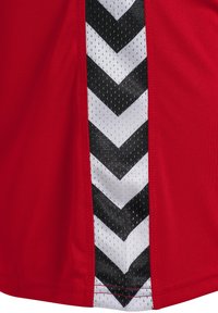 Röd idrottströja med ett svart och vitt chevronmönster på sidan. Tillverkad av smidigt material med en andningsbar meshpanel.