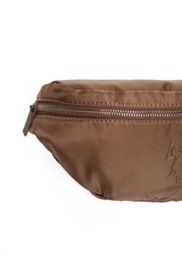 Hnědá nylonová ledvinka se zipovým uzávěrem, s texturovaným materiálem a vyraženým logem na přední straně. Kompaktní a zakřivený design.