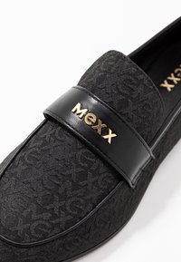 Mocassini neri con tomaia in tessuto testurizzato decorata da un motivo sottile, impreziositi da una fascia in pelle nera lucida e dal logo dorato "MEXX".