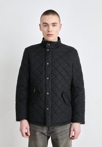 Μαύρο γιλέκο με καπιτονέ ύφασμα, ψηλό γιακά, κλείσιμο με κουμπιά και δύο πλαϊνές τσέπες. Διαθέτει απαλό υλικό και διαμαντένιο μοτίβο σε όλη την επιφάνεια.